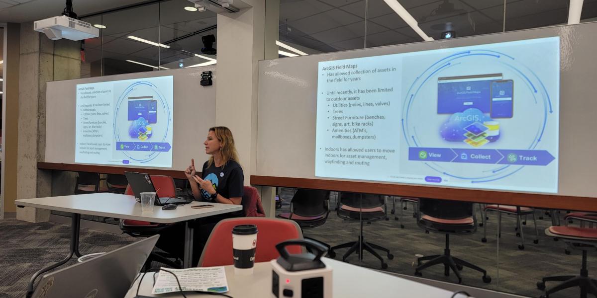 woman sitting between two screens an presenting about mapping