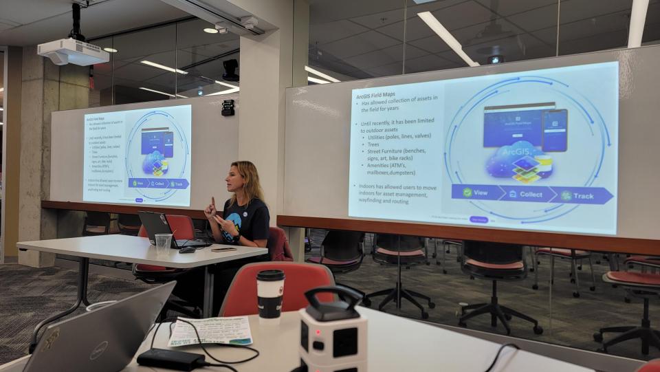 woman sitting between two screens an presenting about mapping