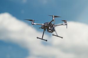 A large, black drone is seen in the sky. 